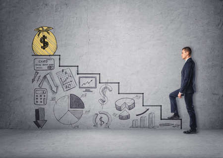 Businessman climbing stairs with economic charts and a bag of money on top of stairs. Believe in yourself. Increase in profits. Making money. Success and development. Setting and achieving goals.の写真素材