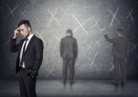 Image of a businessman thinking about how to solve a problem with 'x' marks around him.の写真素材