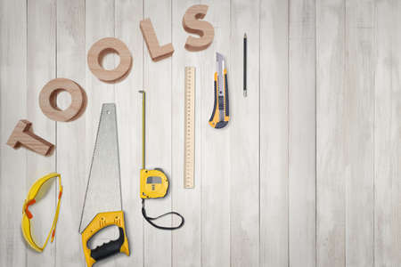 Top view of yellow construction instruments and tools on the white wooden table with 3d word 'tools' above them. DIY. Construction and maintenance. Carpentry works.の写真素材