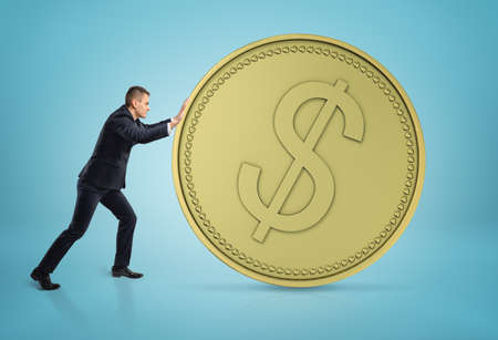 Businessman rolling big golden dollar coin.の写真素材