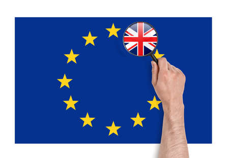 Top view of a man's hand holding a magnifier over EU flag with magnified flag of UK. Brexit. British withdrawal. Significant decision. Substantial choice.の写真素材