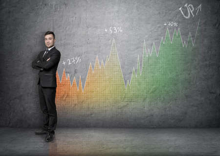 Full portrait of a young businessman with his arms crossed on a background of an increasing graph. Business presentation. Financial chart. Succesful management.の写真素材