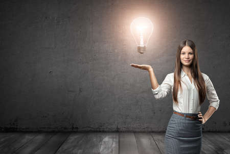 Cropped portrait of a young businesswoman holding big glowing light bulb.の写真素材