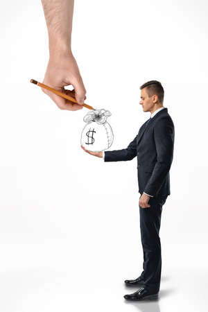 Side view of a businessman holding a hand-drawn bag of money with a big hand that draws it isolated on white background.の写真素材