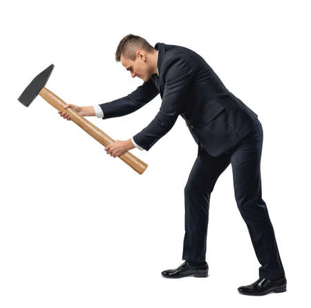 Side view of a businessman with big hammer in his arms destroying something, isolated on white background.の写真素材