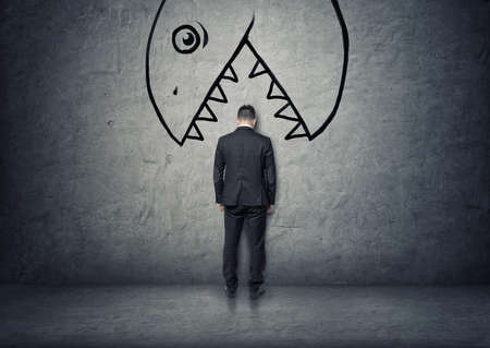 Back view of a businessman with his head between teeth of a bug hand drawn monster to eat him.の写真素材