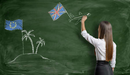 Businesswoman drawing a plane with british flag that flies away from an island with EU flag on blackboard.の写真素材