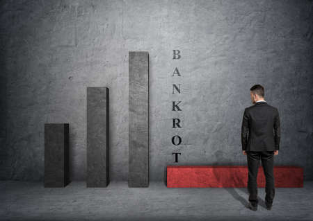Back view of a businessman looking at fallen bar of the graph with 'bankort' word near it.