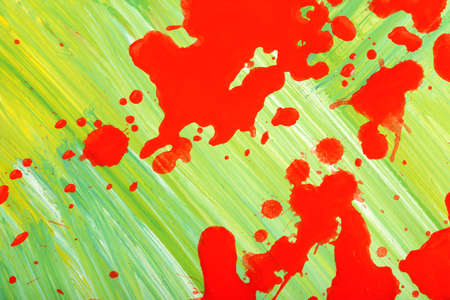Red splashes of paint on a canvas painted green.の写真素材