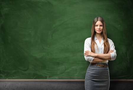 Young businesswoman with glasses standing in front of blank chalkboard.の写真素材