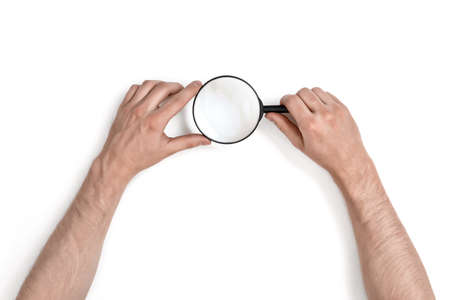 Hands of man holding the magnifying glass isolated on white background.の写真素材
