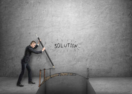 Businessman drawing a bridge over a gap with word 'solution' above it.の写真素材