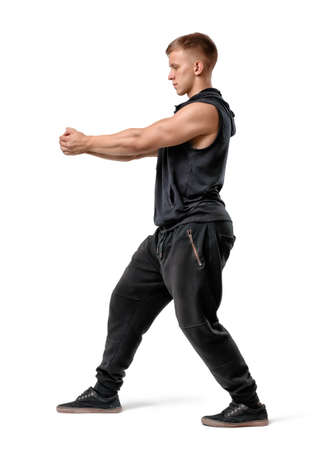 Side view of muscled young man holding something in outstretched arms isolated on white background.の写真素材