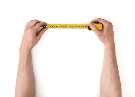 Close-up view of man's hands measuring something with tape-measure isolated on white background.