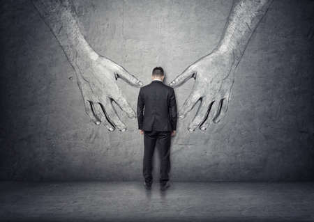 Back view of a businessman standing between big hand drawn hands.の写真素材