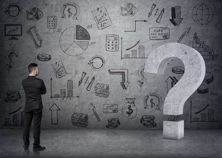 Back view of businessman touching big 3D concrete question mark on the background with business doodles.の写真素材