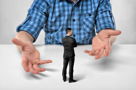 Businessman stands in front of cropped portrait big man sitting with his clasped fingers.の写真素材