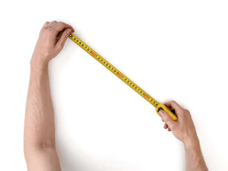 Close-up view of man's hands measuring something with tape-measure isolated on white background. Building and repairing. Handyman. DIY concept.の写真素材
