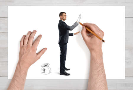 Close up view of man's hands drawing a businessman and a scak of money on sheet of paper with pencil. Earning money. Success and profit. Employment issues.の写真素材