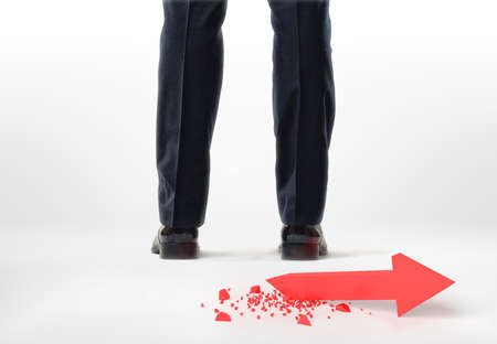 Back view of cropped legs and feet of a businessman with red broken arrow behind him isolated on...