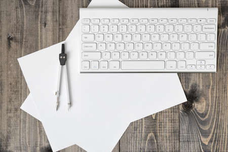 Keyboard, paper and compass on wooden plank. Workplace of architect, constructor, designer in top view. Engineering and Design. Construction and architecture.の写真素材