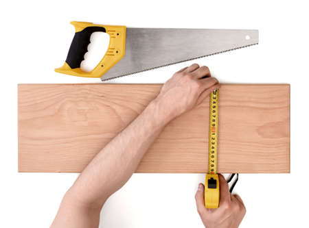 Close up view of a man's hands measuring wooden plank with tape line, isolated on white background. Tools and instruments.の写真素材