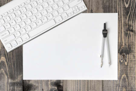 Keyboard, paper and compass on wooden plank. Workplace of architect, constructor, designer in top view. Engineering and Design. Construction and architecture.の写真素材