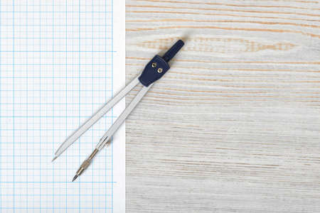 Compass on graph paper in top view with copy space on the right side. Workplace of architect, constructor, designer. Start a new project. Construction and architecture. Tools for drawing.の写真素材