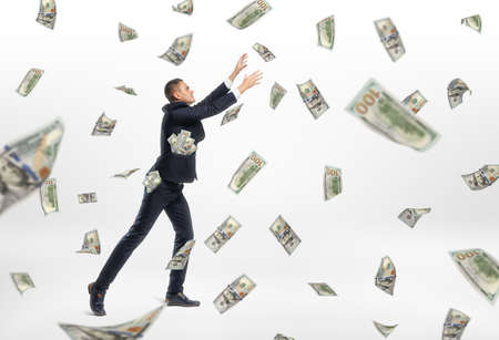 A lot of cash money flying and a businessman catching them on the white background. Success aspiration. Prosperous business. Earning a lot og money.の写真素材