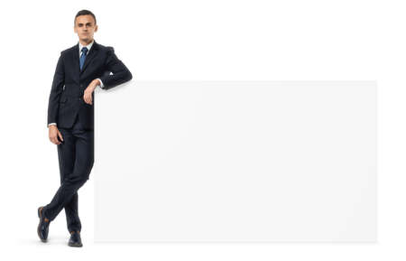 Handsome businessman stands next to an empty banner on white backgroundの写真素材