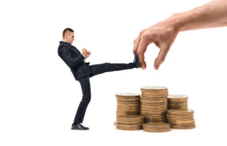 Businessman is hitting with leg huge hand trying to grab his profitの写真素材
