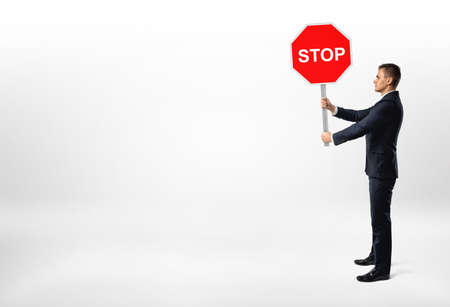 Businessman standing on white background and holding a stop sign.の写真素材