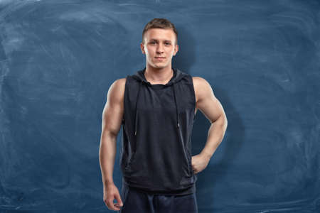Muscular young man in sportswear is standing on the dark blue backgroundの写真素材