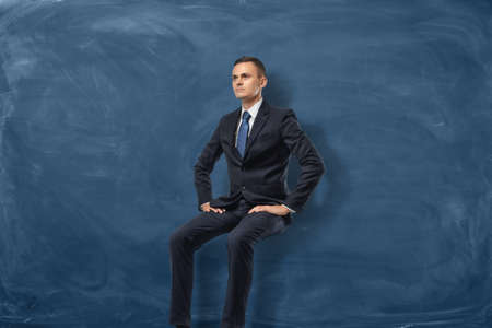 Businessman is sitting and thinking isolated on blue chalkboard backgroundの写真素材