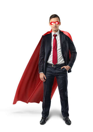 A businessman in a formal suit, a red flowing cape and a red eye mask with one hand in his pocket in front view.の写真素材