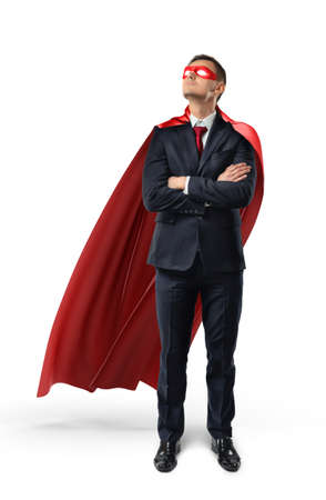 A businessman in an official suit and red cape with hands crossed and looking up.の写真素材