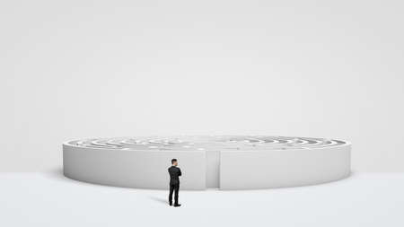 A tiny businessman standing in front of a large white round maze right next to the entrance.の写真素材