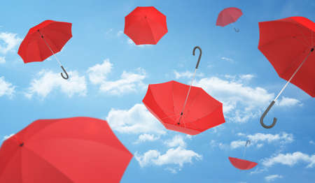 Many open red umbrellas falling from the blue sky dotted with clouds. Weather. Rainy day. Helpful advice.の写真素材