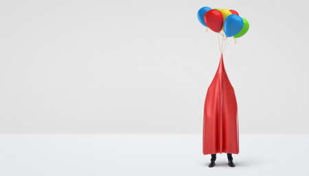 A businessman hidden under a red glossy cloth that has several colorful balloons tied to its center. Uncertainty in business. Unexpected show. Hiding.の写真素材