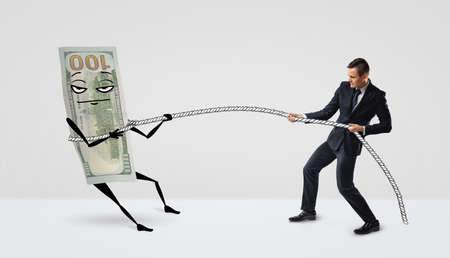 A hundred dollar bill with arms and legs caught in a lasso by a small businessman.の写真素材