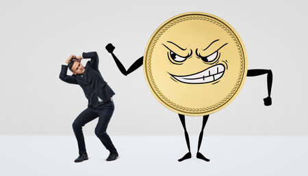 A giant humanoid coin with an angry face beating at a small businessman.の写真素材