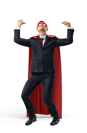 A businessman in superhero costume over his suit trying to hold a heavy invisible heavy object from above.の写真素材