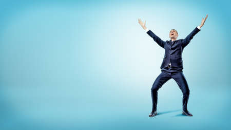 A joyful businessman with a smile on his face and hands raised in victory motion.の写真素材