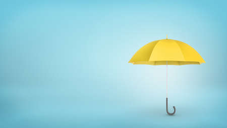 An open classic yellow umbrella with a handle vertically placed on blue background.の写真素材