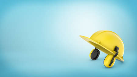 A yellow construction workers hard hat with earmuffs on blue background.の写真素材