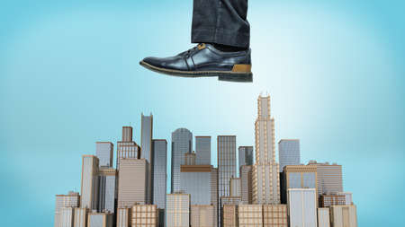 A giant male shoe ready to stomp at a small cluster of business towers on blue background.の写真素材