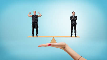 A female hand holding a small seesaw with a businessman an athlete on each sides.の写真素材
