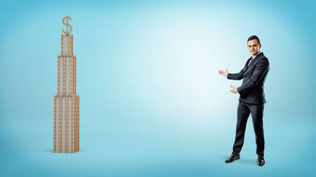 A large businessman showing a business building with a golden USD sign on top.の写真素材