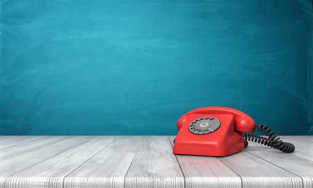 3d rendering of a bright red dial phone standing on a wooden desk and a blue wall background.の写真素材
