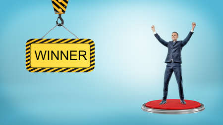 A happy businessman stands on a red pushbutton near a construction sign reading Winner.の写真素材